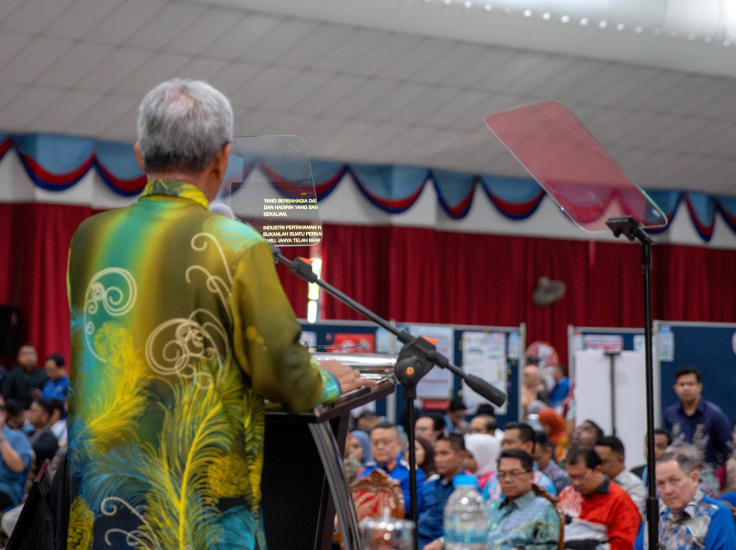 Speaker delivering a speech using Presidential Teleprompter screens at a conference.